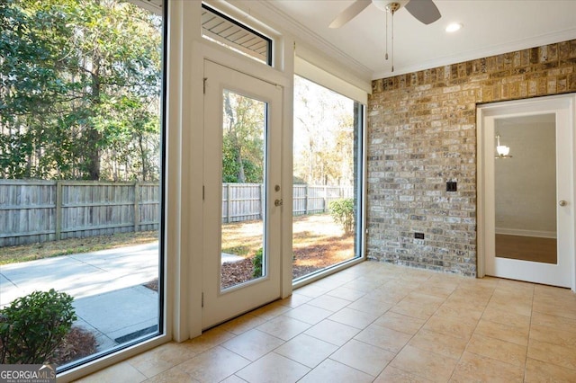 doorway to outside featuring ceiling fan, ornamental molding, brick wall, and light tile patterned floors