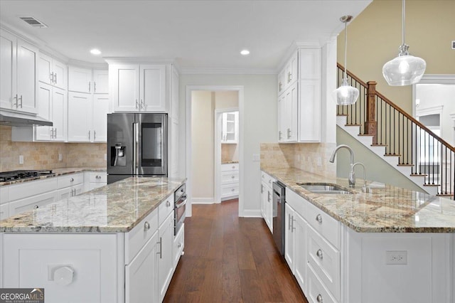 kitchen featuring appliances with stainless steel finishes, decorative light fixtures, sink, and white cabinets