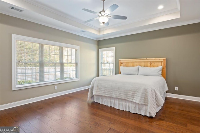 bedroom featuring ornamental molding, ceiling fan, dark hardwood / wood-style flooring, and a tray ceiling