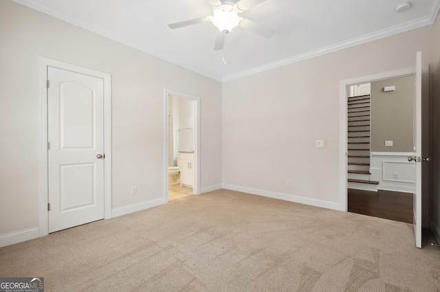 unfurnished bedroom featuring light colored carpet, ornamental molding, and ensuite bathroom