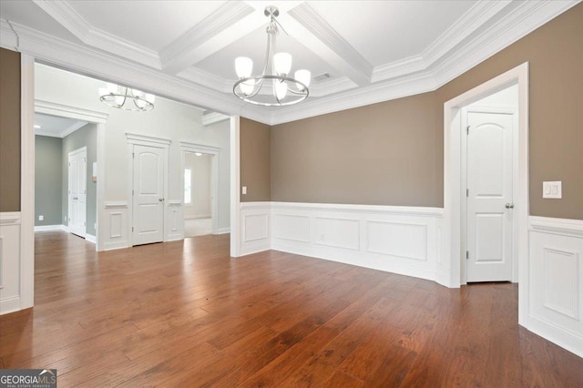 spare room with beam ceiling, dark hardwood / wood-style floors, coffered ceiling, ornamental molding, and a chandelier