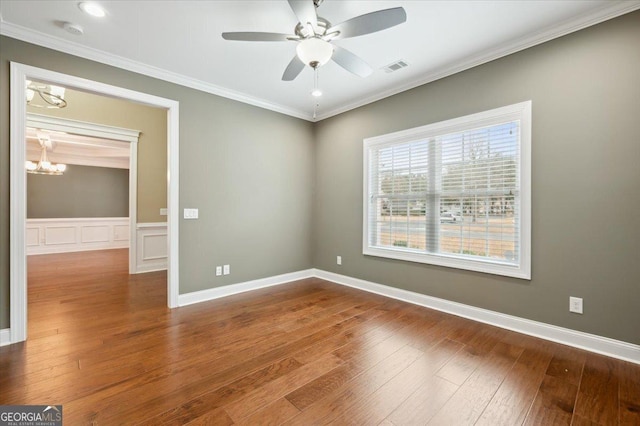 spare room featuring hardwood / wood-style flooring, ceiling fan with notable chandelier, and ornamental molding