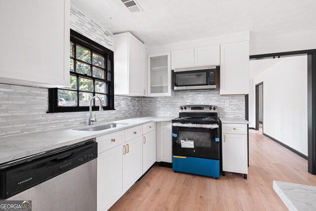 kitchen with stainless steel appliances, white cabinetry, sink, and backsplash