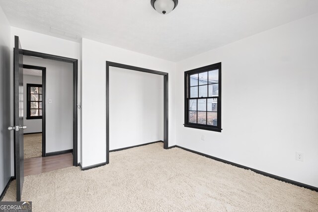 unfurnished bedroom with a closet and light carpet