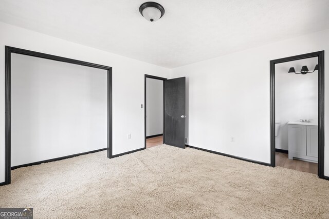 unfurnished bedroom featuring connected bathroom and light colored carpet