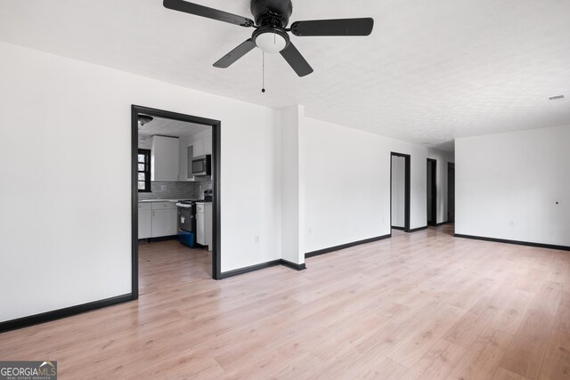 empty room with ceiling fan, a textured ceiling, and light wood-type flooring