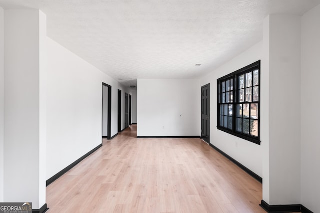 empty room featuring a textured ceiling and light hardwood / wood-style flooring