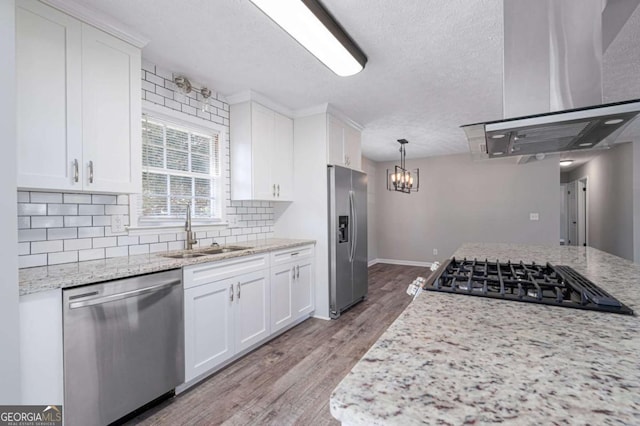 kitchen with sink, white cabinetry, stainless steel appliances, light stone counters, and decorative light fixtures