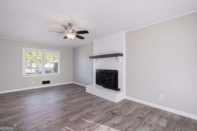 unfurnished living room featuring ceiling fan, dark hardwood / wood-style floors, ornamental molding, a textured ceiling, and a brick fireplace