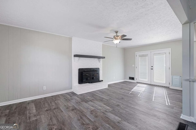 unfurnished living room featuring ceiling fan, a brick fireplace, dark wood-type flooring, a textured ceiling, and french doors