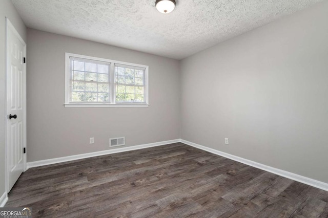 spare room featuring dark hardwood / wood-style floors and a textured ceiling