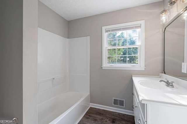 bathroom with vanity, hardwood / wood-style floors, a textured ceiling, and shower / bathing tub combination