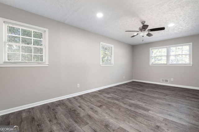 empty room with ceiling fan, dark hardwood / wood-style floors, and a textured ceiling