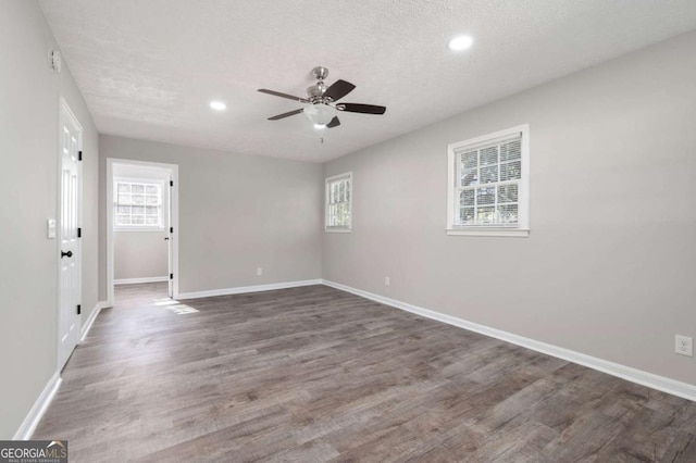 empty room with dark wood-type flooring, ceiling fan, and a textured ceiling