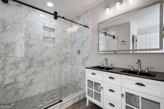 bathroom featuring vanity, a shower with shower door, hardwood / wood-style floors, and a textured ceiling