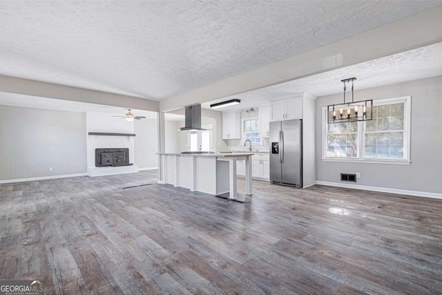 unfurnished living room with ceiling fan with notable chandelier, dark hardwood / wood-style floors, sink, and a textured ceiling