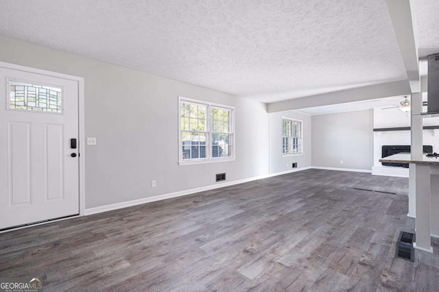 unfurnished living room with ceiling fan, dark hardwood / wood-style floors, a textured ceiling, and a fireplace