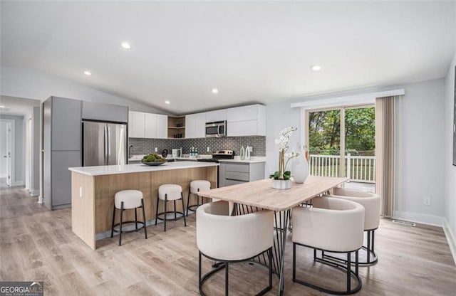 dining space featuring lofted ceiling and light wood-type flooring