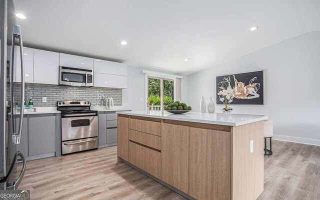 kitchen featuring a kitchen island, tasteful backsplash, white cabinets, light hardwood / wood-style floors, and stainless steel appliances