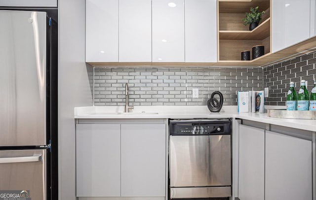 kitchen with tasteful backsplash, white cabinetry, appliances with stainless steel finishes, and sink