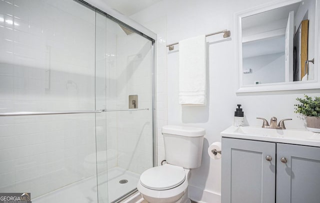 bathroom with vanity, a shower with door, and toilet