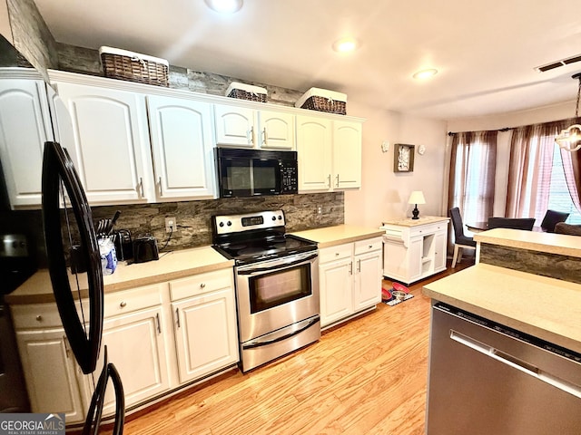 kitchen with visible vents, light wood finished floors, stainless steel appliances, light countertops, and decorative backsplash