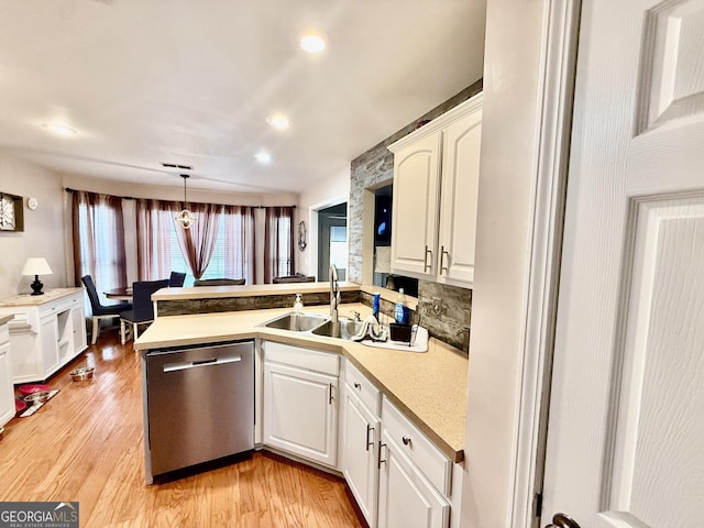 kitchen featuring a sink, white cabinetry, light wood-style floors, a peninsula, and dishwasher