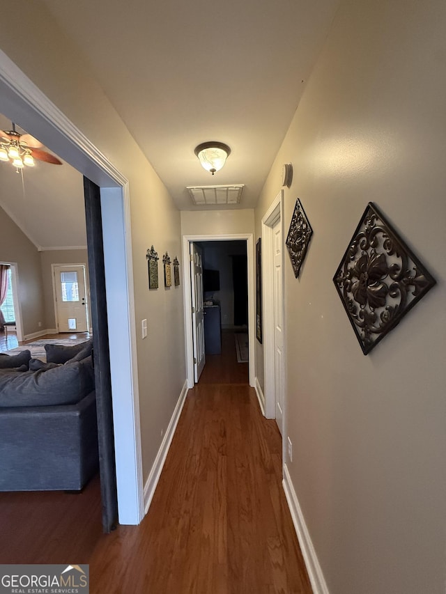 hallway with dark hardwood / wood-style floors and vaulted ceiling