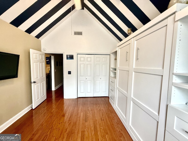 unfurnished bedroom featuring light wood-style flooring, baseboards, visible vents, and high vaulted ceiling