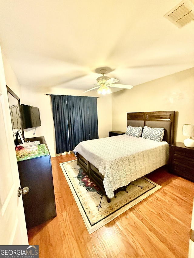 bedroom featuring a ceiling fan, wood finished floors, and visible vents