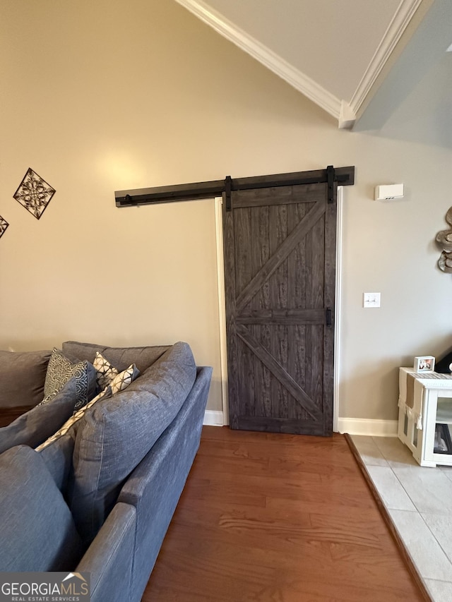 interior space featuring hardwood / wood-style flooring, vaulted ceiling, a barn door, and crown molding