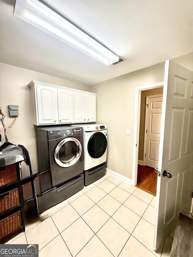 laundry room with baseboards, cabinet space, light tile patterned flooring, and washing machine and clothes dryer