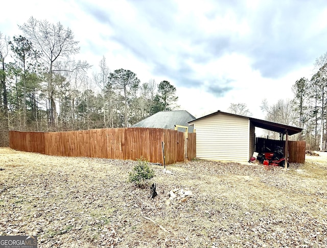 view of yard featuring an outbuilding, driveway, fence, a pole building, and a carport