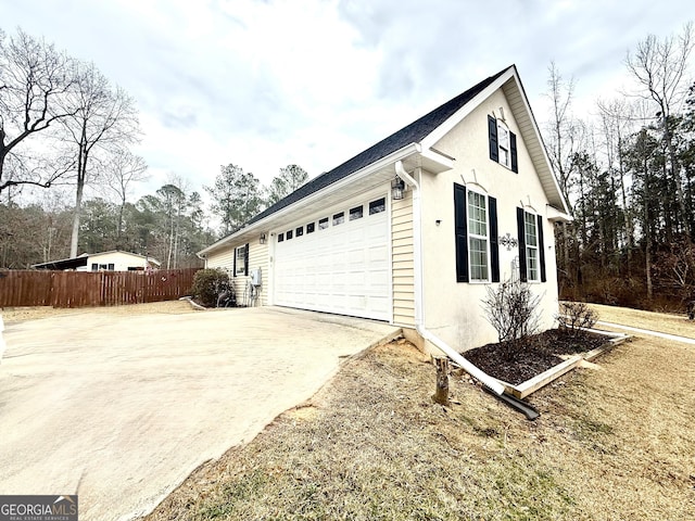 view of property exterior featuring stucco siding, concrete driveway, a garage, and fence