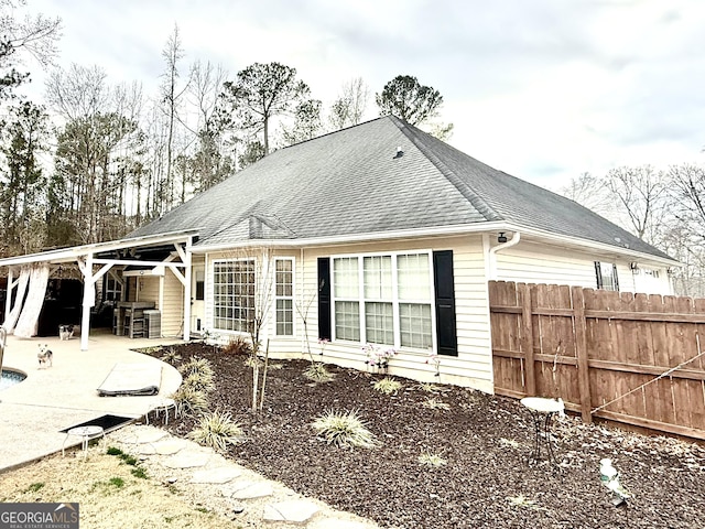 back of property featuring a patio area, a shingled roof, and fence