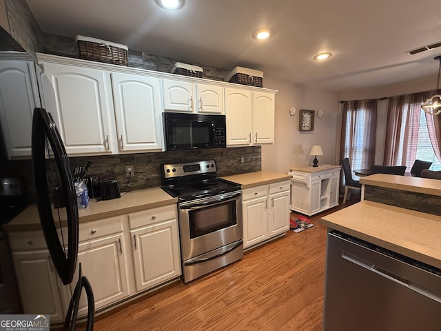 kitchen featuring tasteful backsplash, black appliances, light hardwood / wood-style flooring, hanging light fixtures, and white cabinets