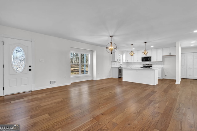 unfurnished living room with light hardwood / wood-style flooring and a notable chandelier