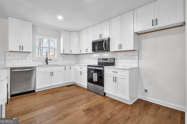 kitchen featuring stainless steel appliances, white cabinetry, sink, and light hardwood / wood-style floors