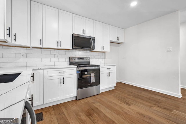 kitchen featuring tasteful backsplash, appliances with stainless steel finishes, light hardwood / wood-style floors, and white cabinets