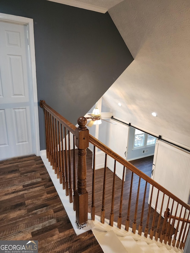 stairs featuring a barn door, wood-type flooring, lofted ceiling, and a textured ceiling