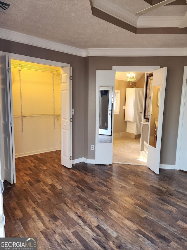 unfurnished living room featuring crown molding, dark hardwood / wood-style floors, and a notable chandelier