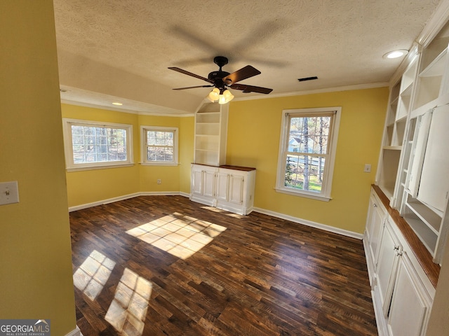 empty room featuring a textured ceiling, dark hardwood / wood-style floors, and a healthy amount of sunlight