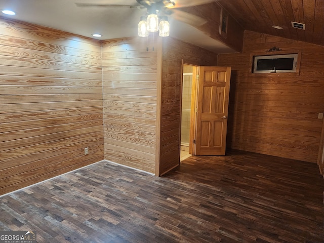 empty room with lofted ceiling, dark wood-type flooring, wooden walls, and ceiling fan