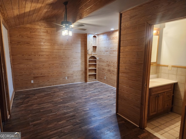 interior space with wooden walls, lofted ceiling, hardwood / wood-style flooring, ceiling fan, and wood ceiling