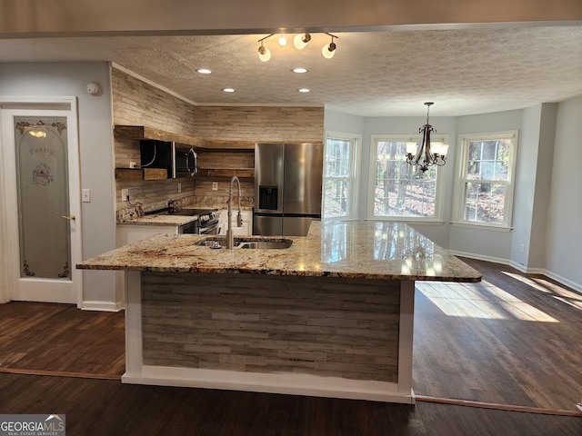 kitchen featuring sink, hanging light fixtures, a kitchen island with sink, stainless steel appliances, and light stone countertops