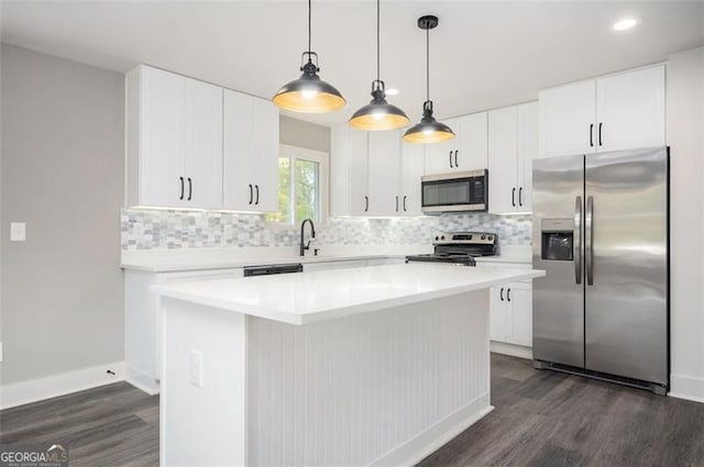 kitchen featuring tasteful backsplash, white cabinetry, appliances with stainless steel finishes, and a center island