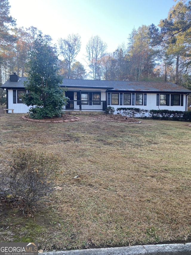 ranch-style home featuring covered porch and a front yard