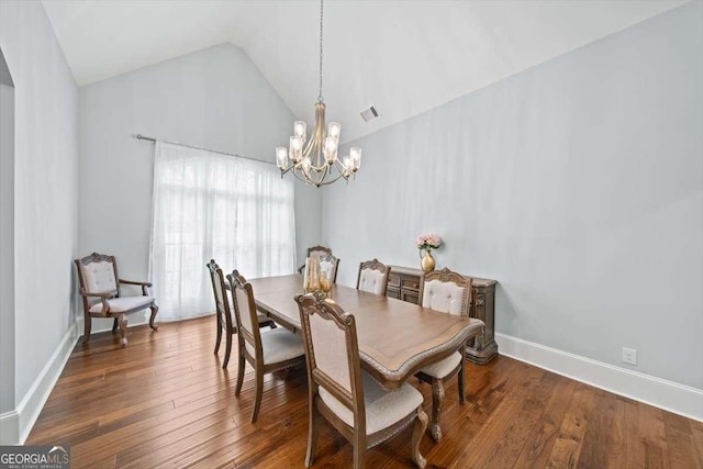 dining space with an inviting chandelier, dark wood-type flooring, and vaulted ceiling