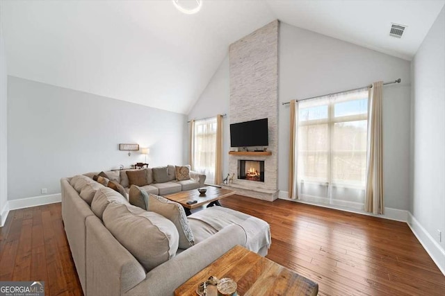 living room with a stone fireplace, high vaulted ceiling, and dark hardwood / wood-style floors