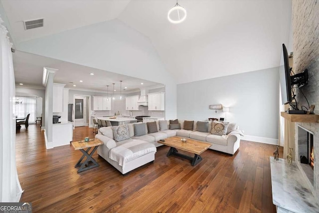 living room featuring ornamental molding, high vaulted ceiling, dark wood-type flooring, and a fireplace